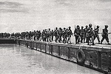 Marching along a harbour wall, Peleliu 